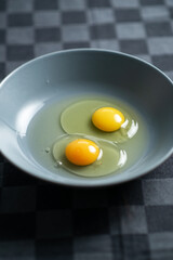 Two raw chicken eggs in a plate on a dark background. Cooking for making food