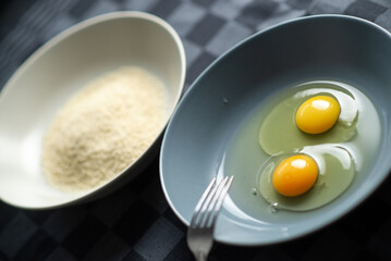 A plate of raw chicken eggs and next to it a washed-out plate with breadcrumbs