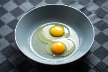 Two raw chicken eggs in a plate on a dark background. Cooking for making food