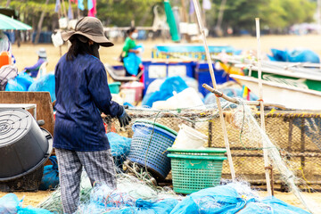 The local fisherman is clearing fishing net at the boat after fishing or working at the sea beach in Thailand. 