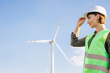 Portrait of woman engineer standing by the windmill turbines