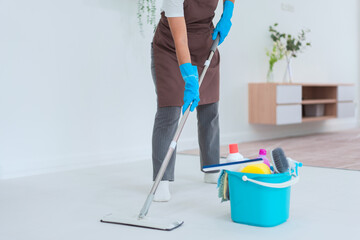 Maid using mop with bucket plastic of cleaner equipment to mopping cleanup floor in living room