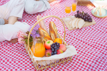 Young couple in love sitting on blanket to picnic with basket of bread fruits and orange juice