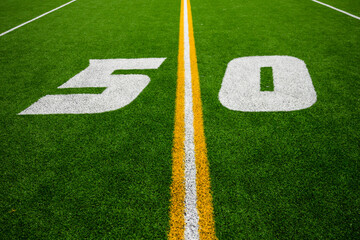 50 yard line on green artificial football field turf