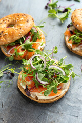 Smoked salmon and soft cheese seeded bagel with pea and purple reddish shoot salad and red onion. Protein packed breakfast concept