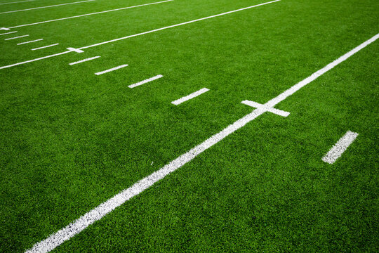 Football field green artificial turf with white lines and hash marks