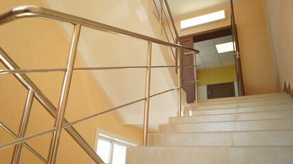 A stairway with a metal railing. New building after construction. Chrome new railings and steps made of tiles.
