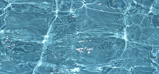 Defocus blurred transparent blue colored clear calm water surface texture with splashes reflection. Trendy abstract nature background. Water waves in sunlight with copy space. Blue watercolor shine.