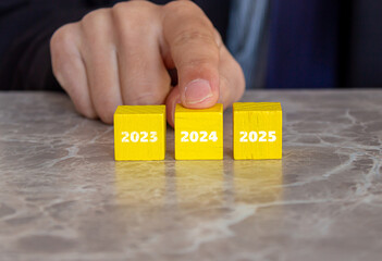Businessman pointing year 2024 on wooden cubes. New business year 2024.