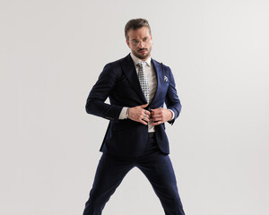 sexy high class businessman with glasses looking away while buttoning suit