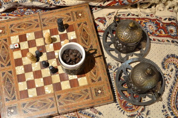 Fototapeta na wymiar Metal cups and Turkish chess board and books in Turkish restaurant