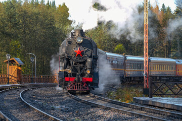 An old steam locomotive with a train arrives at the platform