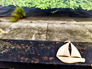 Wooden toy ship sailboat against the background of a river or lake. Concept of traveling by ship or boat. Journey, freedom, wind, peace, exploration