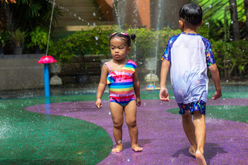 Obraz premium Happy child boy and girl enjoying water splash outdoor water park