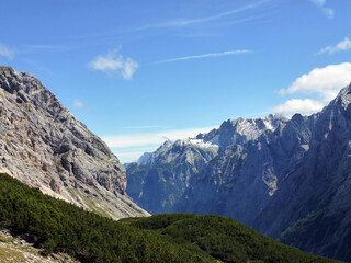 Obraz premium A high mountain with a blue horizon. In the foreground, the slope is covered with green forest. Beautiful natural landscape