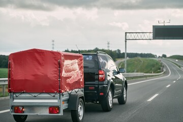 SUV and Rental Cargo Trailer on a Road. Efficient moving. © AlexGo