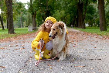 Happy little girl playing with Shetland Sheepdog in the park