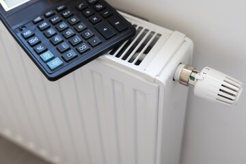 Calculator, banknotes lie on the radiator of the heating system, the cost of heat, utilities