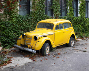 Bright yellow  retro car standing near the house. Old rusty  car.