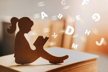 girl with dyslexia holds a book. Flying tangled letters in the air. The child learns to speak and read correctly - obrazy, fototapety, plakaty