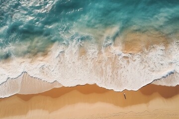cenital view of waves crashing against the sand in an empty beach