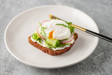 Open sandwich with vegetables and poached egg in a plate on the table