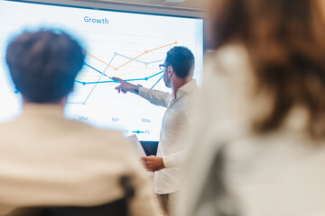 Middle-aged business person explaining financial strategy to a team of investor at the classroom....