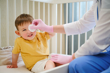 The pediatrician used a white cotton pad to gently clean the baby's delicate skin during their...