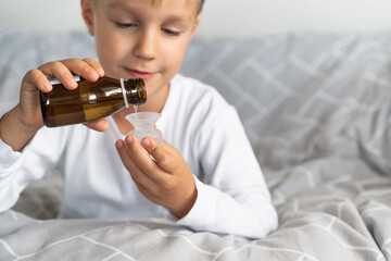 Cough syrup in the bottle. Cute toddler boy holding in hands natural syrup. Health medicine...