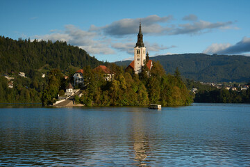 Assumption of Maria Church located on an island on Lake Bled in Slovenia. A boat carrying trussites to the island in the foreground