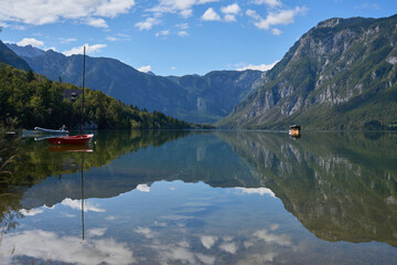 Panoramic view of Lake Bohinjsko in Slovenia. A boat with tourists is sailing on the lake. Mountains in the background