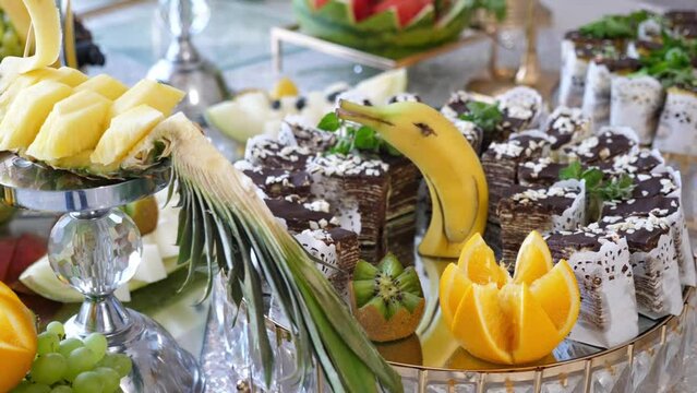 Sweet cakes, pastries and fruits are beautifully laid out on the buffet table. Festive sweet table.