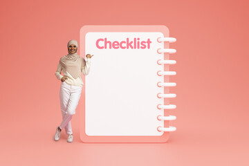 Happy confident young arab woman in casual and hijab point finger at checklist with empty space