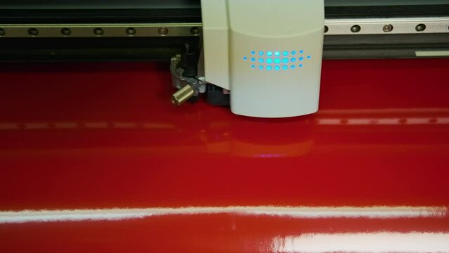 Close up footage of Commercial plotter is cutting a red paper