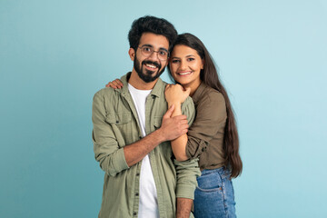 Fototapeta premium Portrait of happy young eastern couple embracing on blue