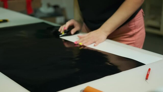An employee of a print workshop tears off a vinyl film before gluing