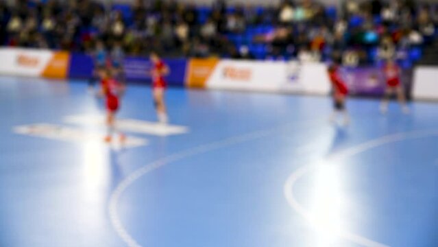 A women's sports team plays indoor handball. Blurry.