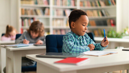 Black schoolboy sitting attentively at desk in class