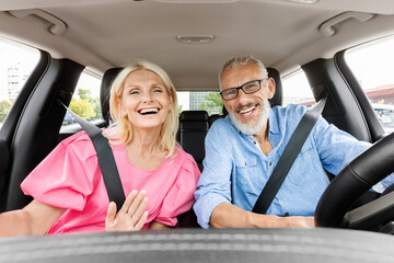 Happy elderly couple have car ride, taking selfie