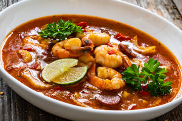 Louisiana soup gumbo with shrimp, chorizo and white rice on wooden table 