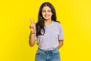 Happy Indian young woman showing victory sign, hoping for success and win, doing peace gesture,...