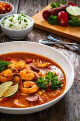 Louisiana soup gumbo with shrimp, chorizo and white rice on wooden table 