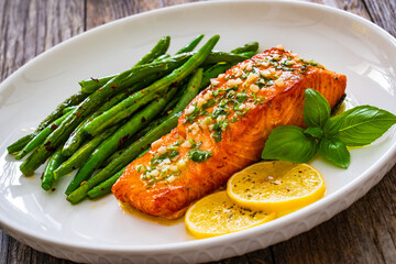 Seared salmon steak with green bean and lemons on wooden table

