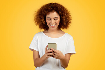 Teen woman engaged in lively chat via phone, yellow background