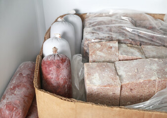 Frozen meat packages in freezer. Many sausages and blocks. Raw food diet or barf for dogs, cats and...