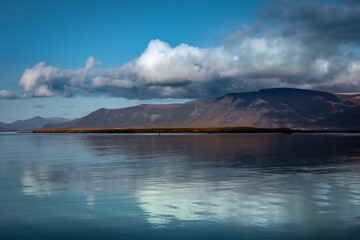 Landscape with Mount Esja and Atlantic ocean in Reykjavik, Iceland. Shining water, cloudy sky. 