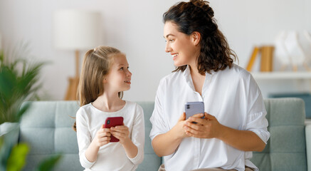 Young mother and daughter using phones