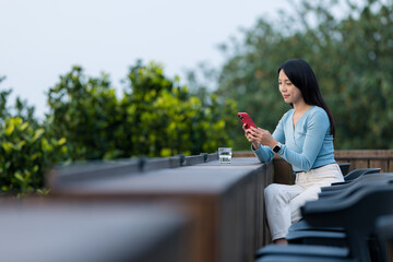 Woman use mobile phone and sit outdoor the coffee shop