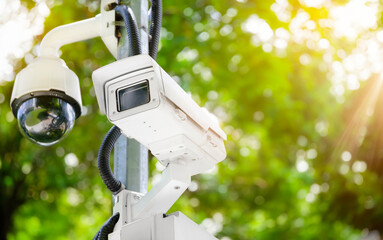 Modern public CCTV camera on a electric pole with blurred natural background.