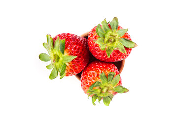 Three ripe strawberries sitting inside a wooden bowl top down view